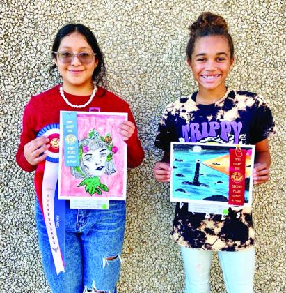 Aracely Cortez and KK Brannon display winning art entries from last year’s Titus County Fair. COURTESY PHOTOS
