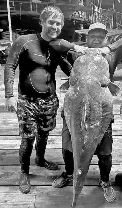 Justin White (left) and Drew Moore recently caught and released this massive 98.7 pound flathead catfish with their bare hands while noodling at Lake Tawakoni. The men plucked the fish out of an underwater cave in 14 feet of water at the base of a bridge.