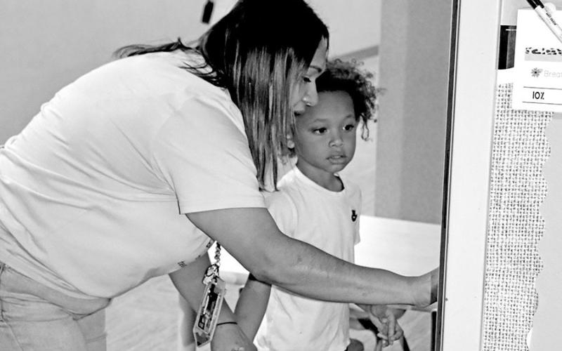 Kayda Alvarado at the Child Development Center shows a new student how to enter the classroom each day.