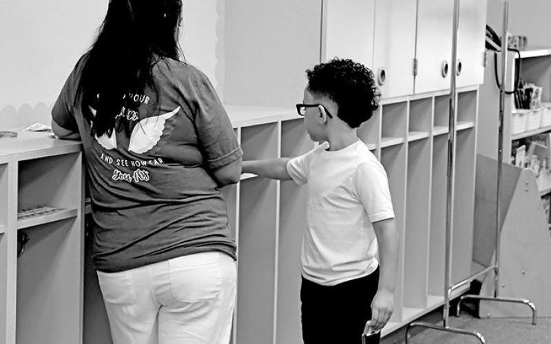 Ofelia Ramirez shows a student his cubby at Fowler Elementary.