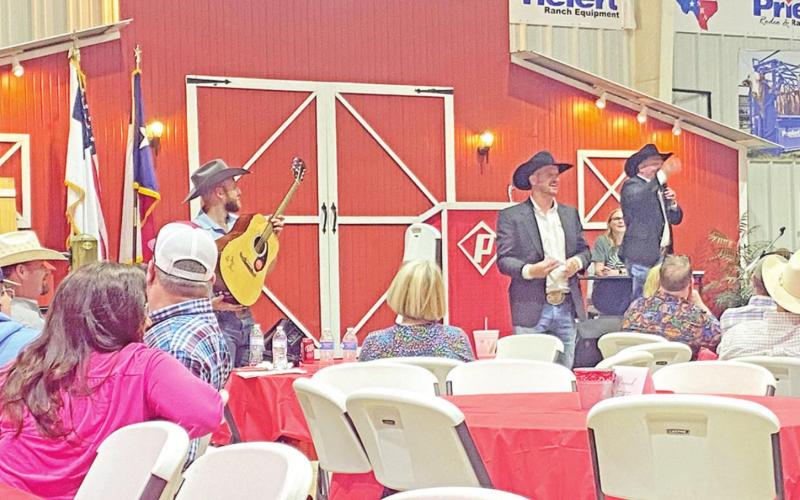 Auctioneers take bids on the autographed George Strait guitar.