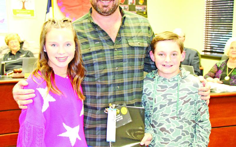 Ella and Jake Anderson present Luke Anderson with a gift from Wallace Middle School