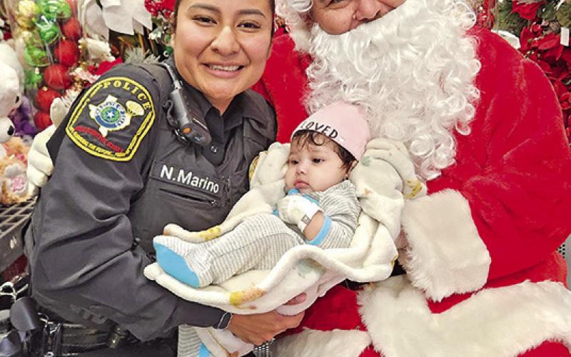 Officer Nataly Marino dotes on a baby and poses with Santa during ‘Shop with First Responders’ TRIBUNE PHOTO / NICOLE KIMBALL