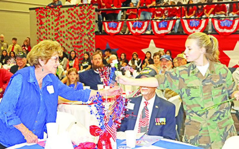 Wallace student, Emi Chappell, presents a carnation to a veteran’s wife. COURTESY PHOTOS
