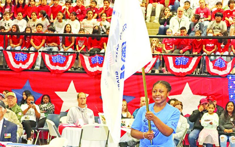 Wallace student, Cassidy Burns, presents the Coast Guard flag.