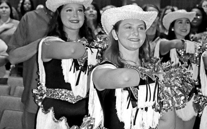 Tiger Dolls Preslee Craig (left) and Marley Broach salute the flag.