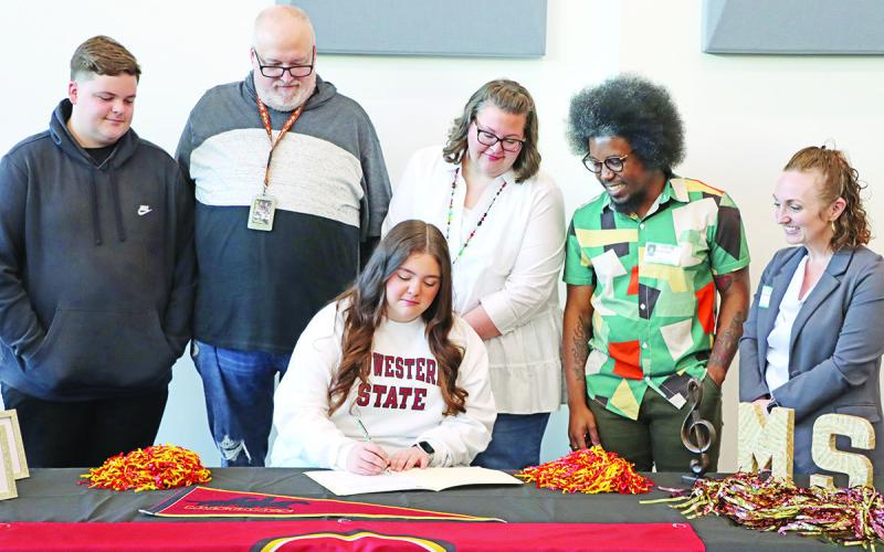 Zoe Newman (center) signs her letter of intent with (L to R) brother Zachary Newman, dad Marty Newman, mom Rhonda Newman, MSU Saxophone Instructor Rafael Powell, and MSU Associate Professor and MPHS alum, Dr. Jennifer Bohannon McGowen COURTESY PHOTO