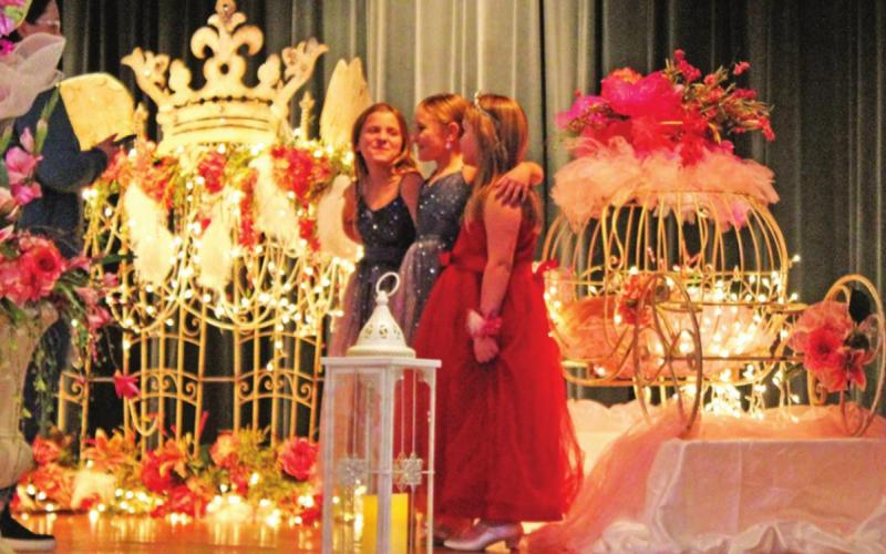 Three young ladies pose on the beautifully decorated stage.