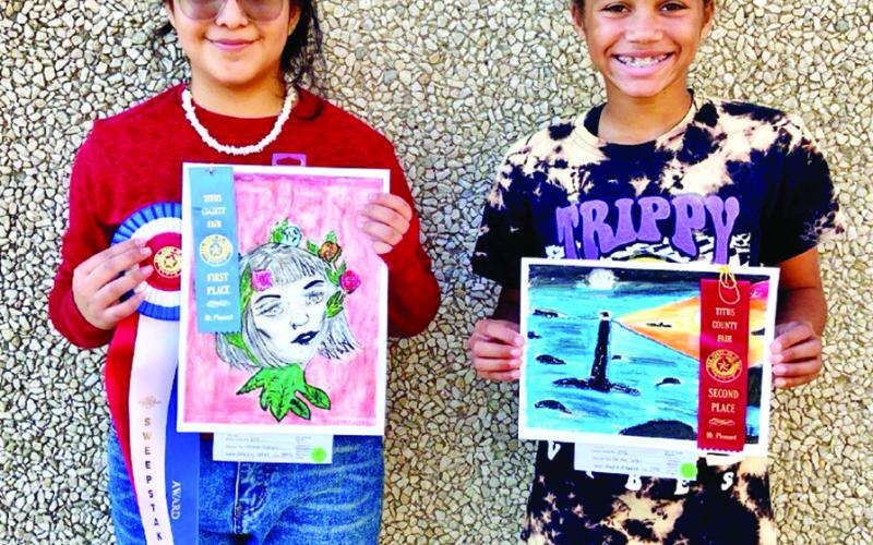 Aracely Cortez and KK Brannon display winning art entries from last year’s Titus County Fair. COURTESY PHOTOS