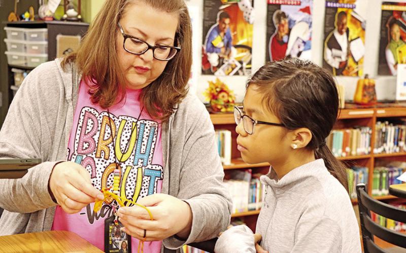 Club sponsor, Rhonda Newman, helps Mia Jimenez