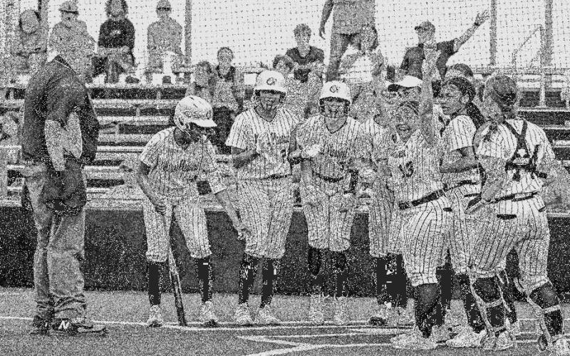 Her teammates wait at home plate to celebrate Rayleigh White’s three-run homerun.