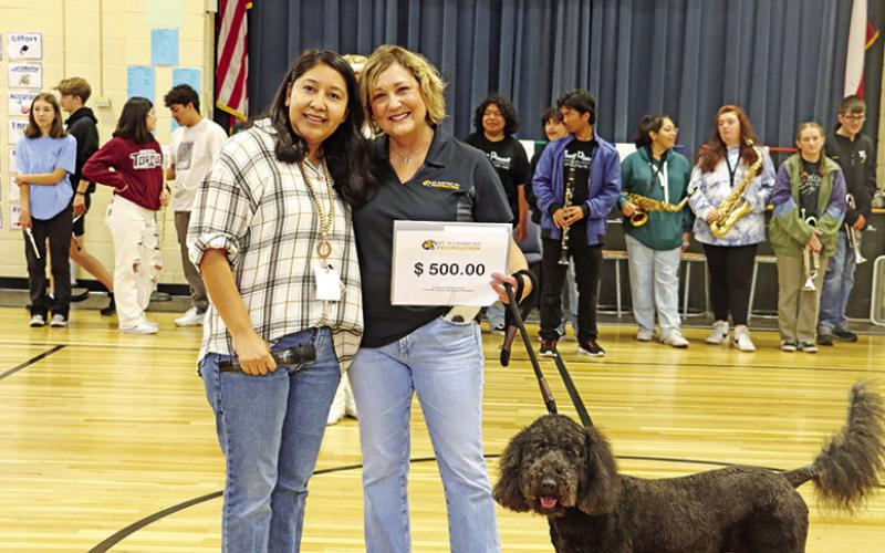 Corprew teacher, Esmeralda Martinez (left), receives a grant from Foundation member, Charla Bowen (center), and MPISD Therapy Dog, Georgia (right)