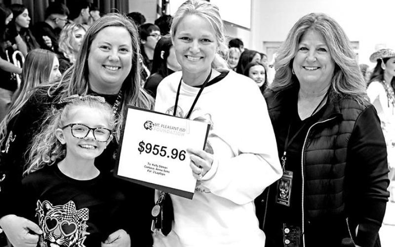 Kelly Silman (center) receives a grant for classroom laptops from (L to R) MJ Cluley, Courtney Cluley, and Tonya Murray