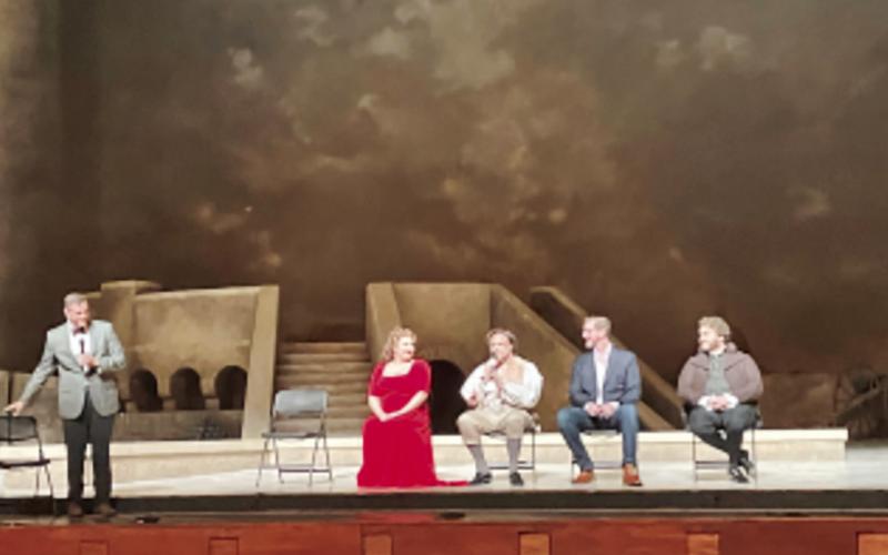 Opera cast membrers on stage talking.