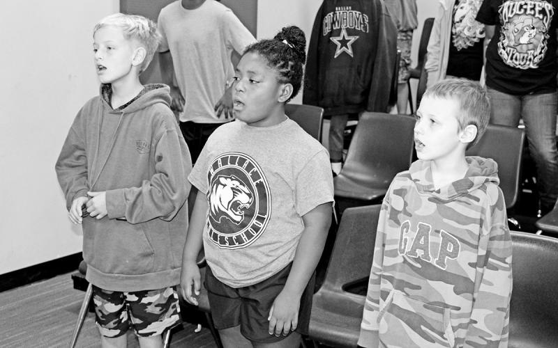 Jeremiah Campbell, Jaicee Amador-Oluwatoke, and Loagyn Hurley sing a folk song in music class.