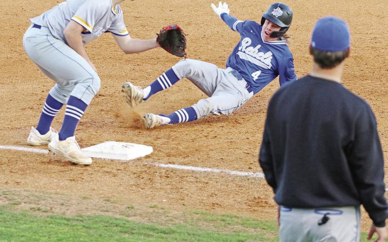 Rivercrest’s Cason Fields slides into third base as Harts Bluff’s Hunter Green awaits the throw. The Rebels defeated the Bulldogs, 12-1, Tuesday at NTCC’s Eagle Field at Bob Baker Stadium.