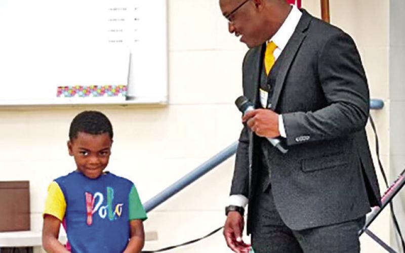 Luke Craddock (right) opens Career Day festivities with assistance from Fowler kindergartner, Ace Rape (left)