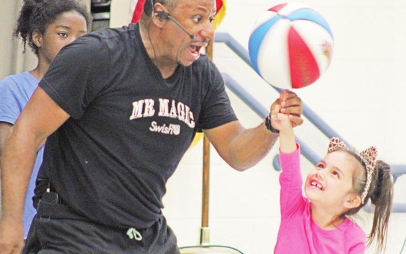 Motivational speaker Mr. Magic Buffy Coleman helps an E.C. Brice student spin the ball on her finger. TRIBUNE PHOTO / QUINTEN BOYD