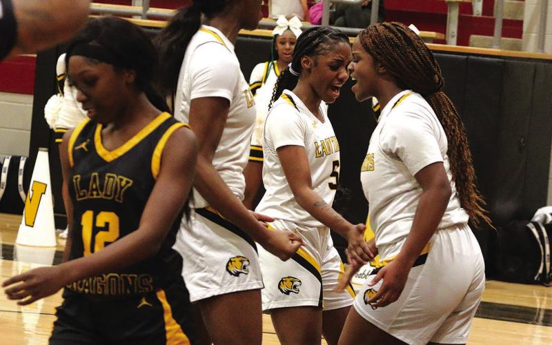 From left, Mount Pleasant’s Aziyah Farrier, Kendall Walker and Jordyn Hargrave celebrate after a layup by Hargrave during Monday’s playoff game against Nacogdoches. The Lady Tigers won, 82-44, and will meet Crandall in the area round this weekend. PHOTO BY QUINTEN BOYD