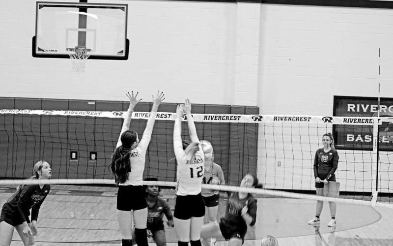 Rivercrest’s Emma Johnson and Anna Duvall jump for a block during Friday’s match against Detroit. The Lady Rebels will finish second in district play and open the playoffs next week against Linden-Kildare. TRIBUNE PHOTO / QUINTEN BOYD