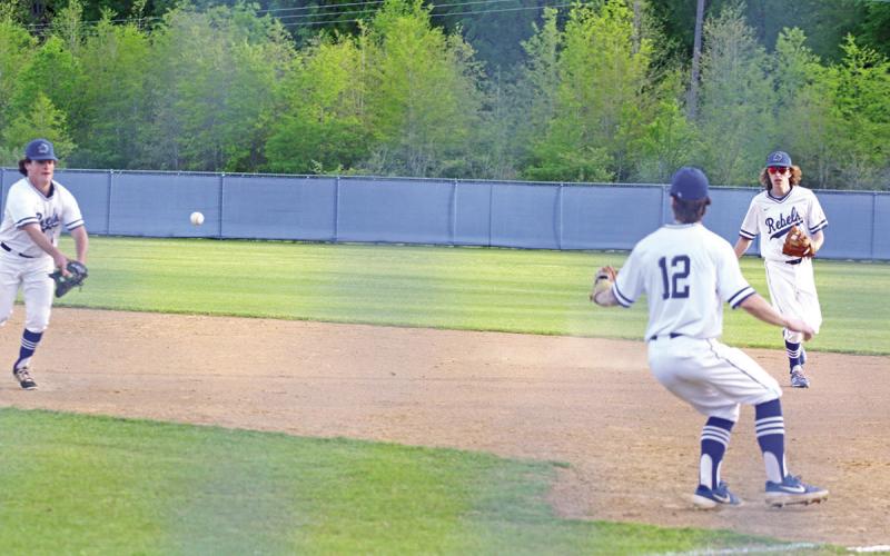 Rivercrest’s Ethan Taylor flips a ball to Mark Grider while Chase Duffer backs up the play during a recent game. Going into their final regular season game Tuesday, the Rebels were tied for third in district with Ore City and Linden-Kildare. TRIBUNE PHOTO / QUINTEN BOYD