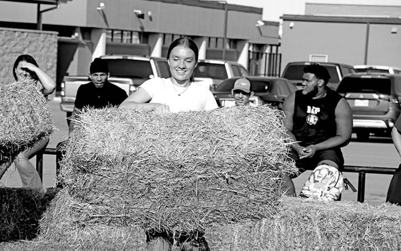 Alexia Hawkins races to stack a bale of hay