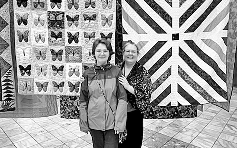 Dr. Karyn Skaar with her daughter, Solveig, in front of the two quilts she displayed in the exhibit. COURTESY PHOTO