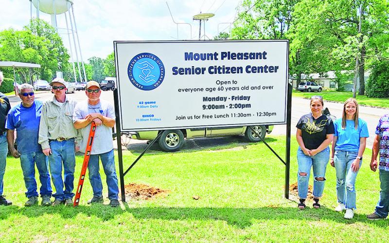Members of Legendary Concepts and Giving Cheerfully pose with the new sign for the Senior Citizen Center