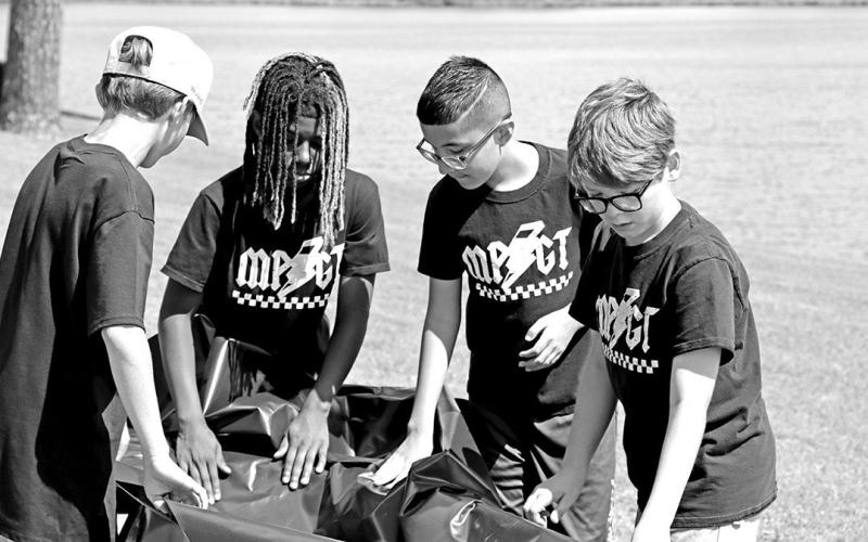 (L to R) Lane Richardson, Jamari Meeks, Joseph Adame, and Benji Baker discuss how to use the plastic tarp
