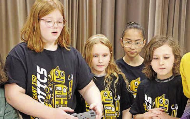 Aryana Knieriem (left) of the Corprew Titans guides their robot with the controller while teammates (L to R) Nylah Bell, Valeria Palacios, and Jace Kline look on.