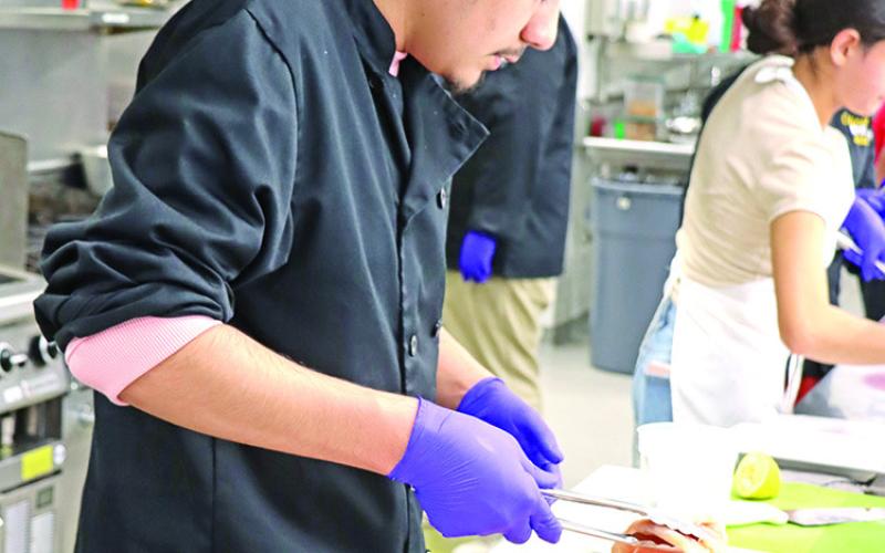 Senior Christian Terrones gets the chicken ready to be grilled