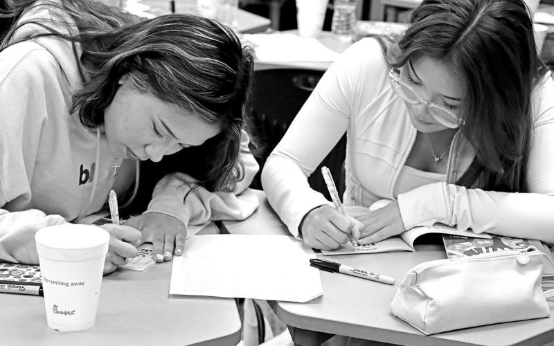 NHS seniors Melanie Barraza (left) and Dollian Phan personalize the books they will give during the 1 million book giveaway event