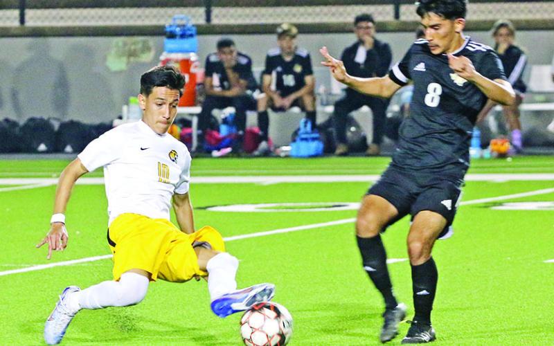 Mount Pleasant’s Ernesto Hernandez slides in to take possession away from Nacogdoches’ Bryan Morales during Thursday’s playoff game. Hernandez scored the game-tying goal near the end of the first half, but the Tigers fell to the Dragons in penalties, 3-2. TRIBUNE PHOTOS / QUINTEN BOYD