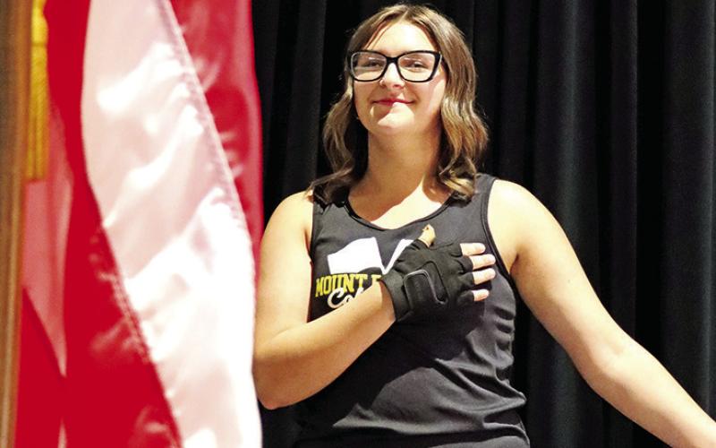 Colorguard member, Zoey Cato, salutes the flag while the band plays the National Anthem