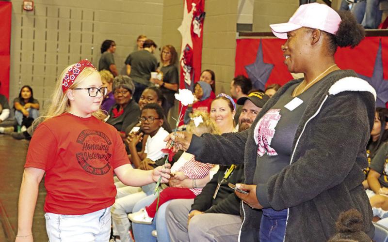 Wallace fifth grader, Kate Cluley, presents a carnation to a military spouse