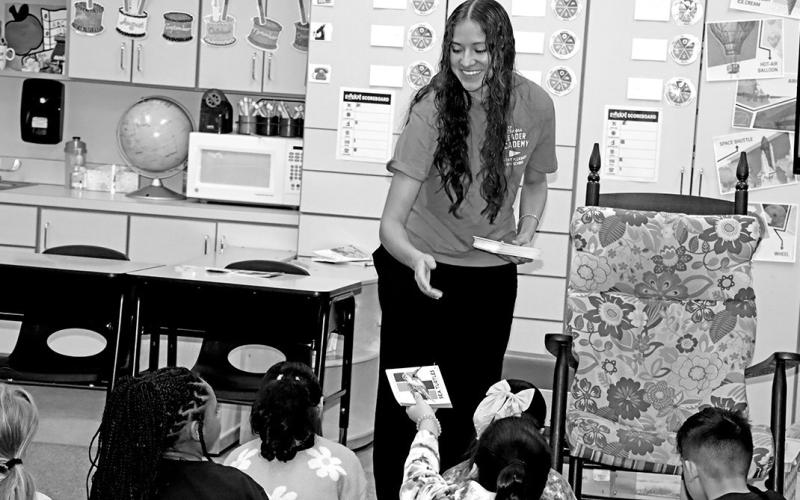Esme Perez hands out books at E.C. Brice