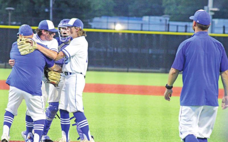 Rivercrest coach Chad Jenkins and players Mark Grider and Cayden Williams embrace Ethan Taylor after game two’s final out. Taylor racked up the complete game win as well as collected the game-winning RBIs to close out the series. TRIBUNE PHOTO / QUINTEN BOYD