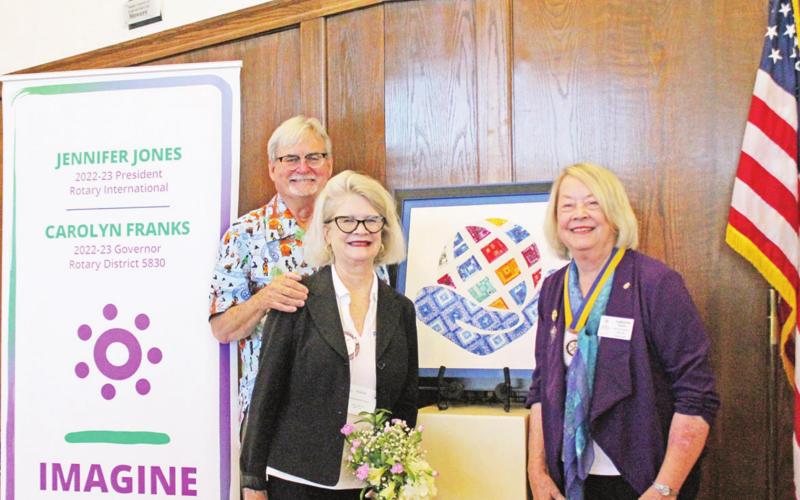 In keeping with an unwritten custom, Carolyn Franks (right) presents Mike Groom (2021-2022 District Governor) and his wife Andrea with a framed representation of the previous year’s theme to the outgoing Governor. Last year’s theme was “Serving to change lives.” GAZETTE PHOTO / ELIZABETH LANNING