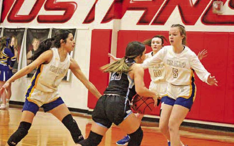 From left, Harts Bluff’s Alexa Arzate, Kaitley Green and Kaylee Clay defend Como-Pickton’s Bella Romero during Monday’s playoff game. The Lady Bulldogs fell in the program’s first ever basketball playoff game but return eight of their nine players next season in the hopes of returning to the playoffs. TRIBUNE PHOTO / QUINTEN BOYD