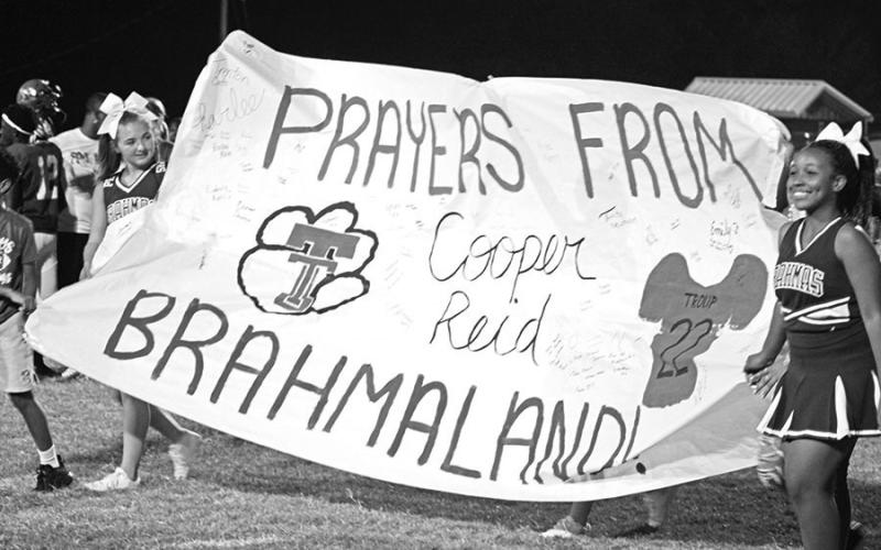 Pewitt cheerleaders present a banner in honor of injured Troup Tiger Cooper Reid to the Troup contingent immediately following Friday’s game. TRIBUNE PHOTOS / QUINTEN BOYD