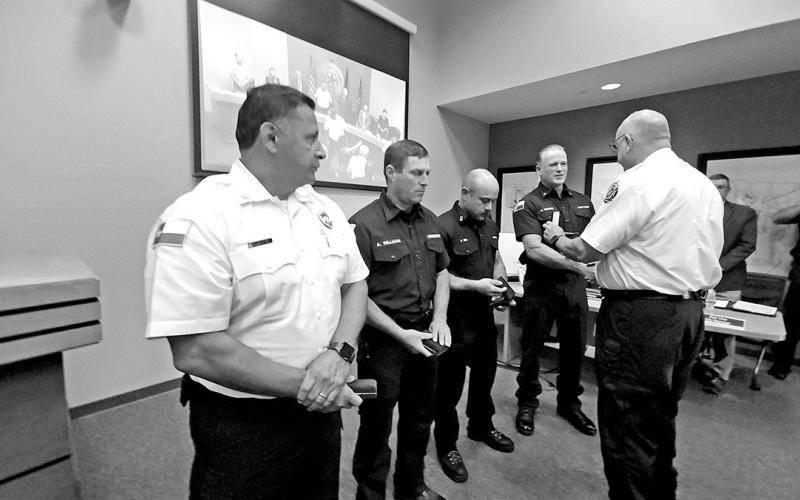 Four firefighters receive the Fire Department’s Life Saving Medal from Chief McRae