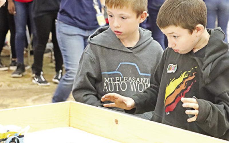 The Cowbots team watches as their robot moves according to their programming.