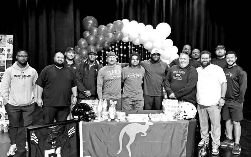 Tyland Jones (center) with members of the MPHS Football coaching staff Courtesy Photos