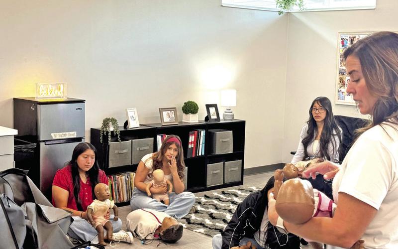 Kristi Houchin (right) demonstrates proper CPR technique on an infant