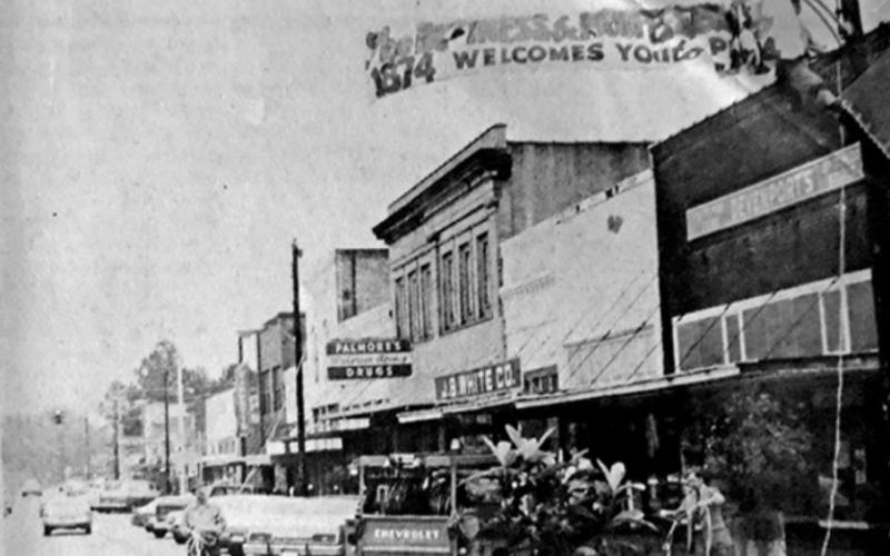 Street Banner--Don Zachary, Bill Elmore and Oscar Hughes put up the Business and Professional Women’s Club Main Street banner promoting the Centennial.