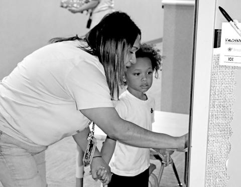 Kayda Alvarado at the Child Development Center shows a new student how to enter the classroom each day.