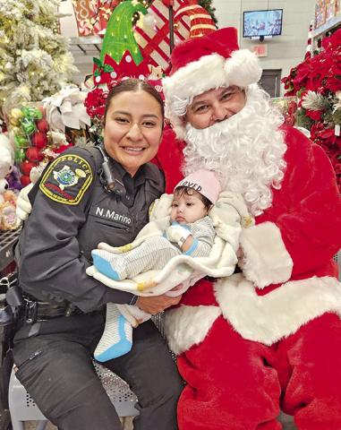 Officer Nataly Marino dotes on a baby and poses with Santa during ‘Shop with First Responders’ TRIBUNE PHOTO / NICOLE KIMBALL