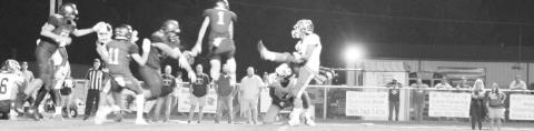 Carson Whitley (center) and Connor Young jump to block an extra point during Friday’s game.
