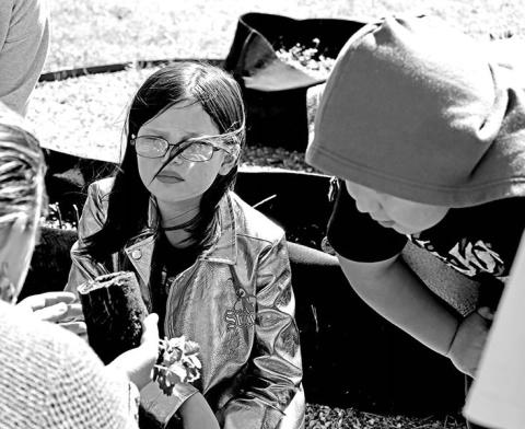 Gabriella Sunderland (left) and Micah Vasquez listen as Advisor Cassie George explains how to transfer the plant from a container to the bed