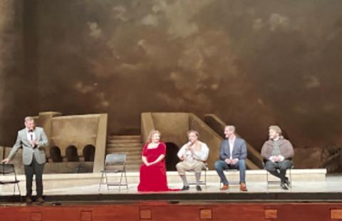 Opera cast membrers on stage talking.